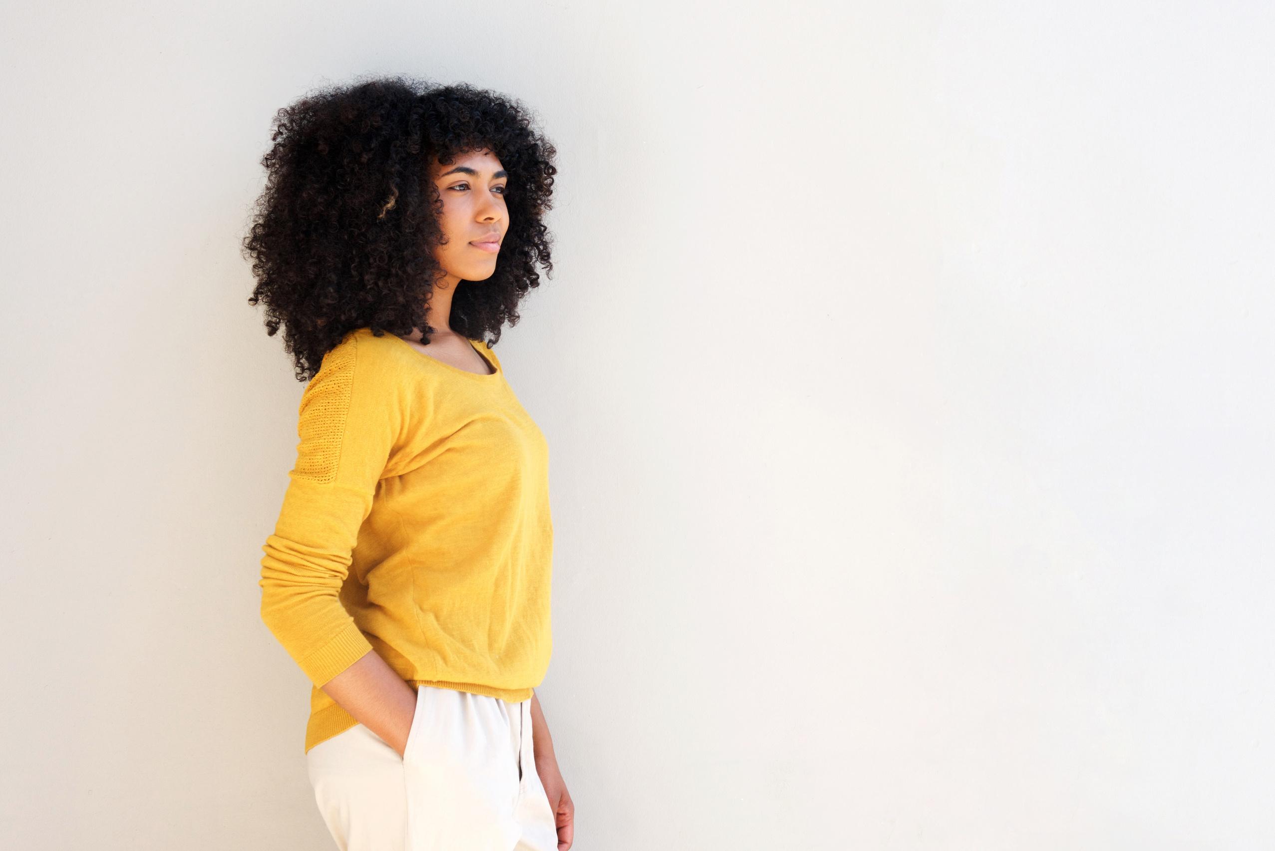 Woman with Afro Hair Leaning on a Wall