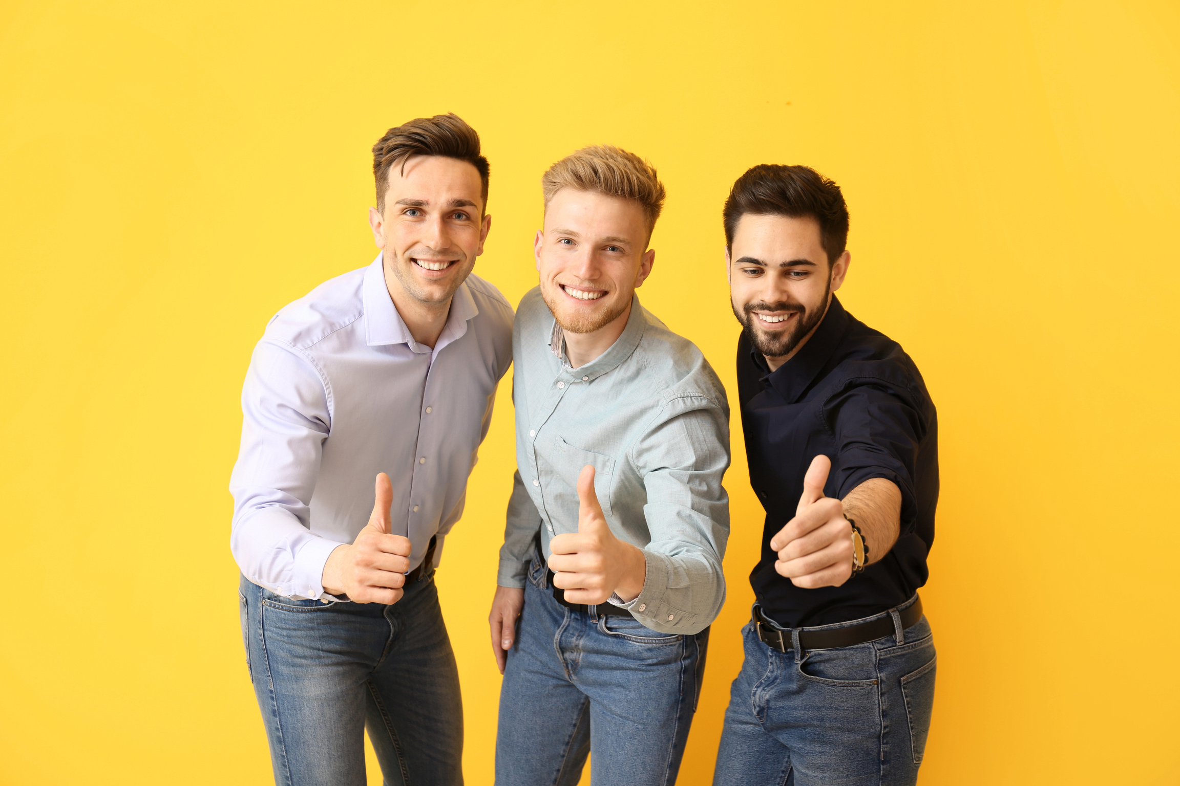 Happy Young Men Showing Thumb-up Gesture on Color Background